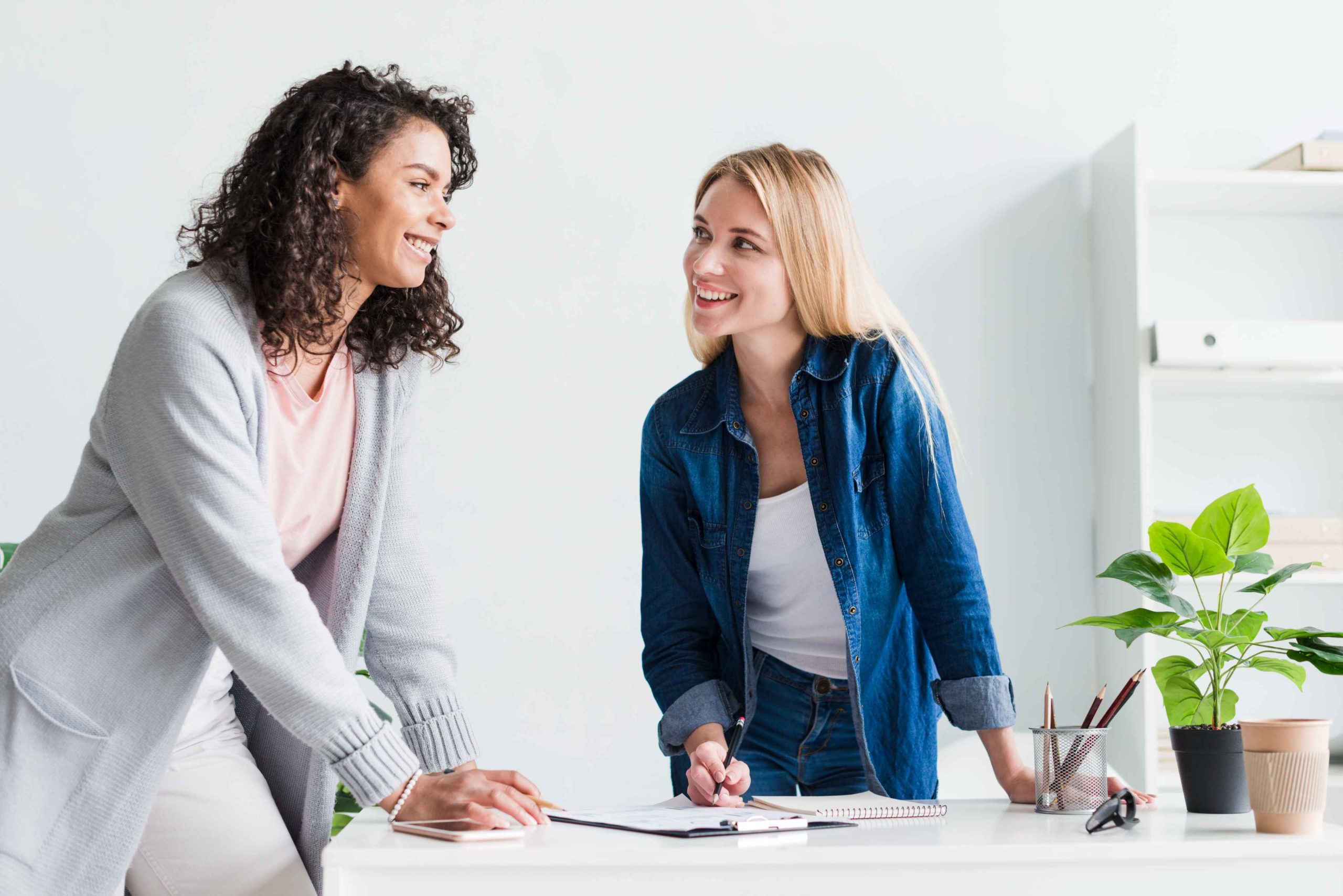 friendly female colleagues discussing work laughing office ()
